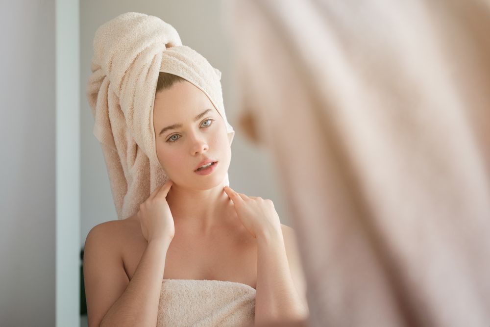 Serene woman in towel looking in mirror