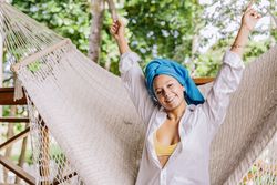 Pleased woman in turban resting in hammock on terrace