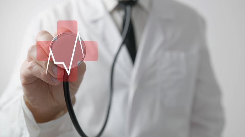 Doctor uses stethoscope with heartbeat hologram