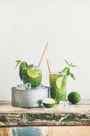 Iced green drinks with lime and mint, with eco friendly straws on light background, with copy space