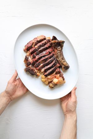 Hands with sliced meat on plate