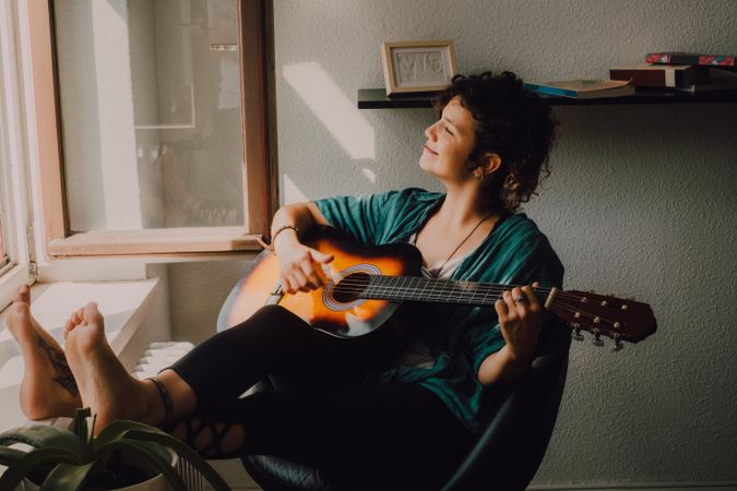 Content woman playing guitar at home