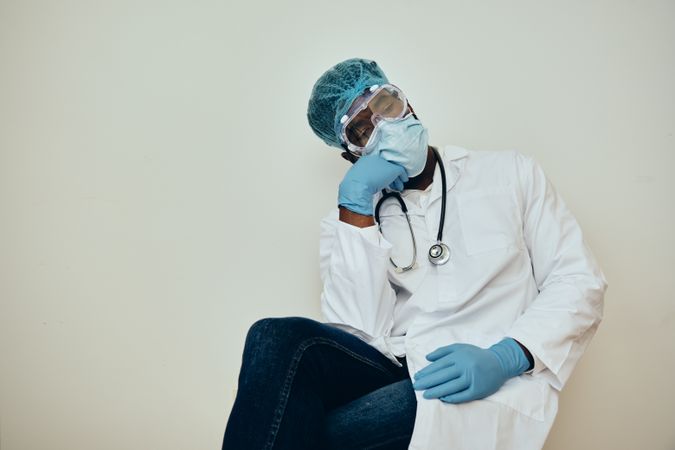 Sad Black male doctor in ppe gear with hand to his head