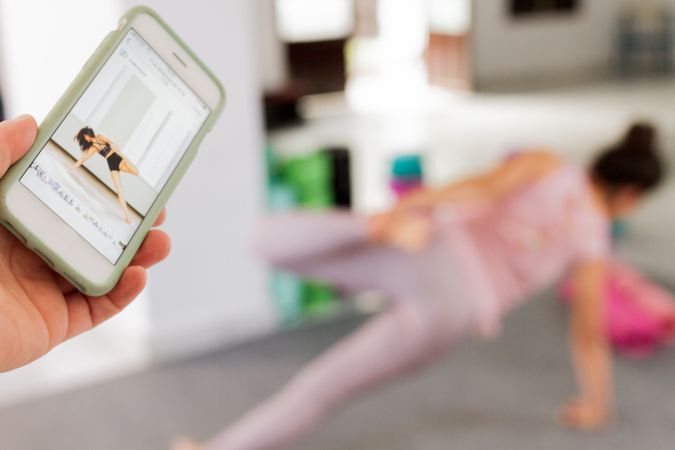 Person holding smartphone against woman doing yoga