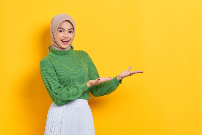 Woman in headscarf presenting yellow copy space