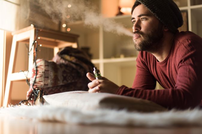 Portrait of man smoking an electric cigarette in christmas decorated room