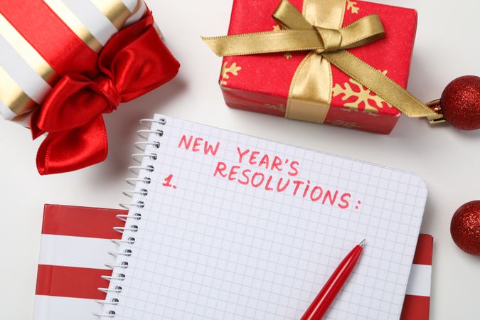 Gift boxes and notepad with list on light background, top view