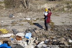 Woman holding her baby in rubble and garbage 5weY6b