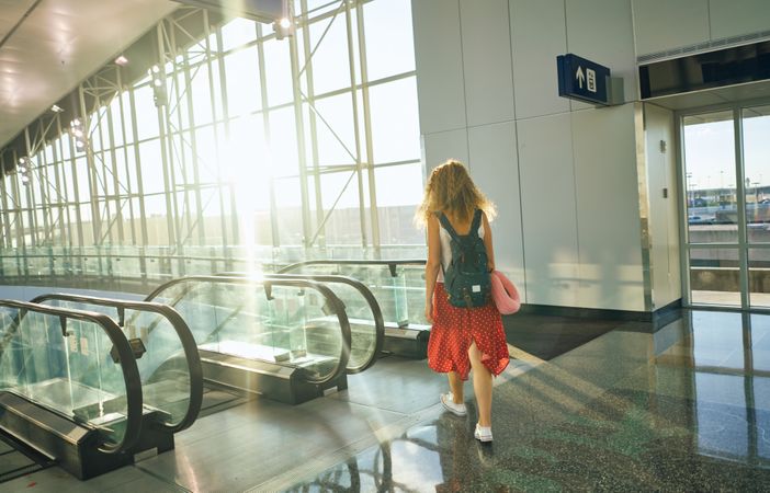 Active woman standing at escalator and about to go down