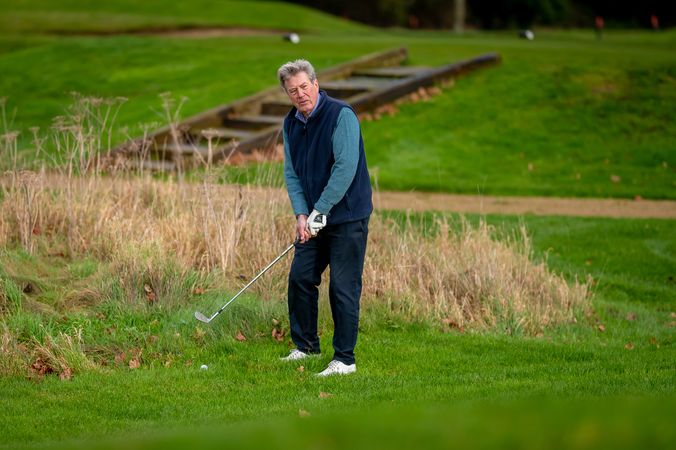 Man swinging club on golf course