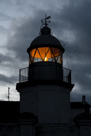 Shining lighthouse against cloudy sky