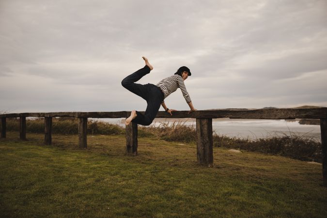 Woman jumping near bench on shore near water