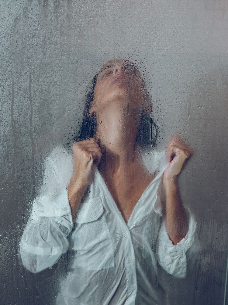 Sensitive woman in wet shower cabin