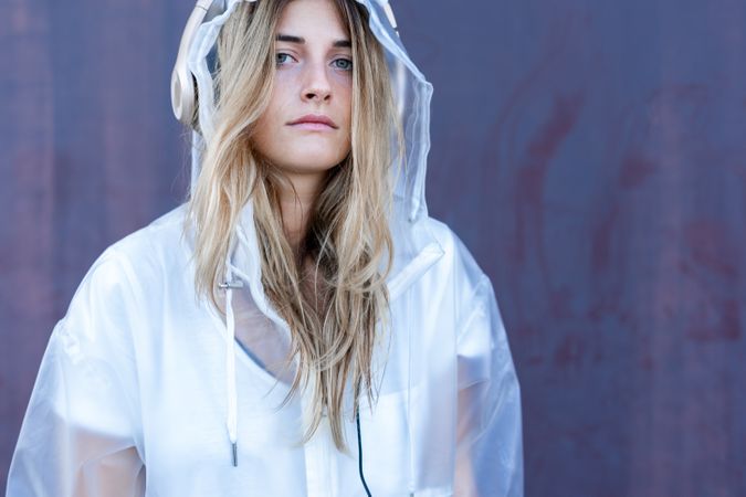 Charming stylish woman in raincoat sitting near wall