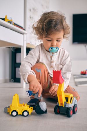 Adorable toddler playing with plastic toys at home