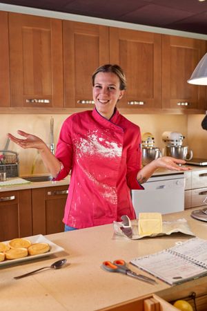 Smiling female pastry chef with dirty uniform looking at camera