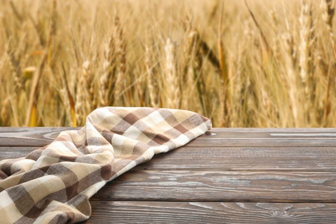 Wooden table with towel against field. Agriculture concept