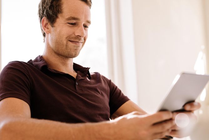 Close up of smiling young man working on digital tablet