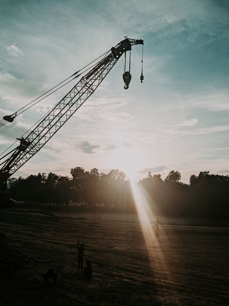 Silhouette of crane near grass field