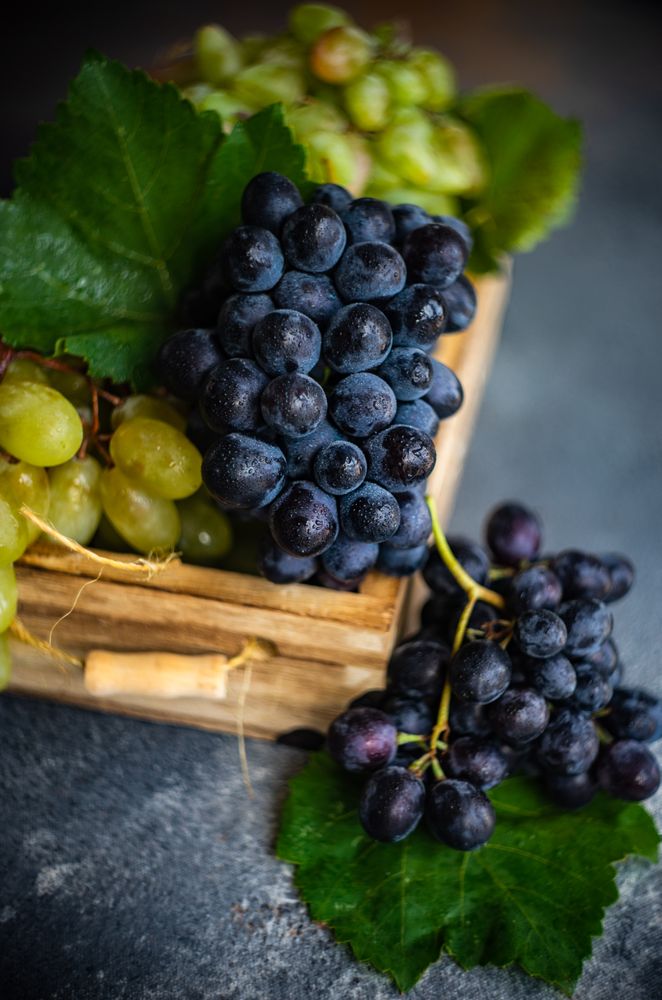 Close up of box of fresh green & red grapes on grey kitchen counter