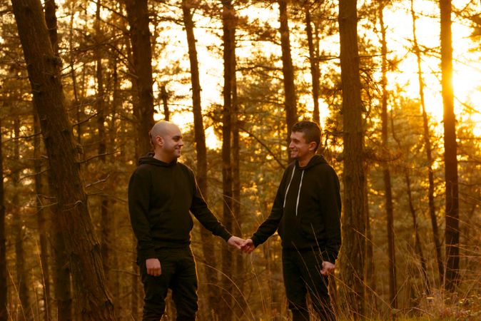 Men holding hands and walking in forest