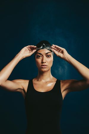 Confident woman in swimming costume on dark background