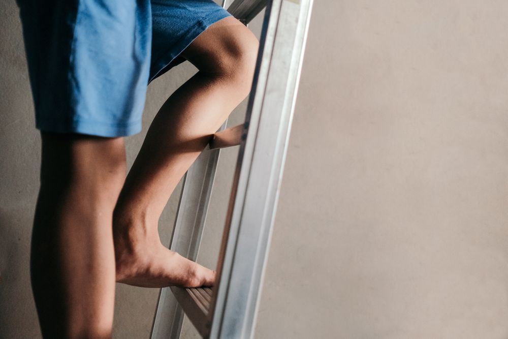 Close up of person’s legs climbing up a ladder