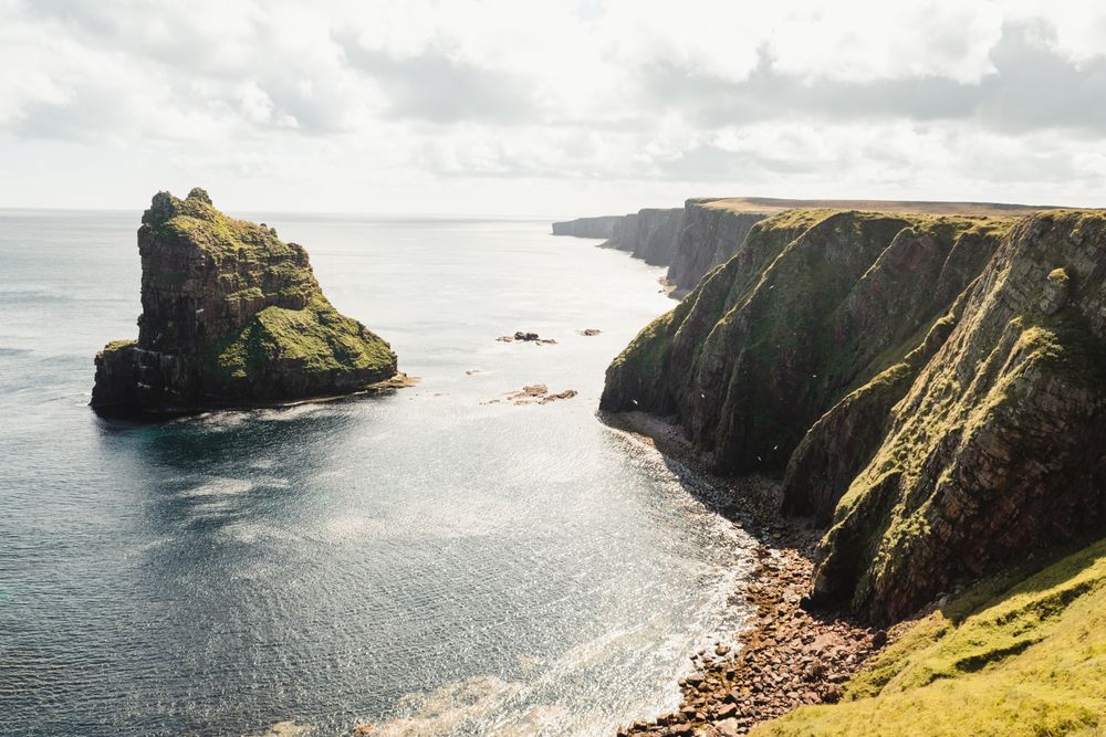 Rocky coast among tranquil ocean water in sunny day