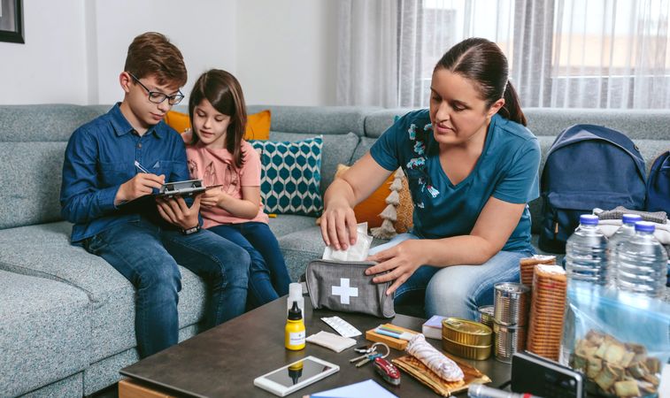 Mother preparing emergency backpack with her children