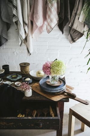 Table with flowers in vase on trays near towels hanging on thread