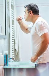 Man brushing teeth in bathroom during morning routine