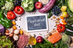 Top view of a healthy food mix fresh vegetables, fruit and fish with chalkboard in center