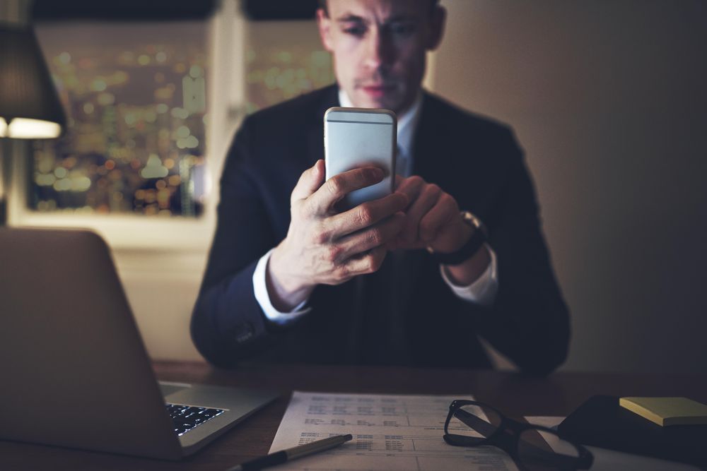 Professional businessman texting at his desk while working at night