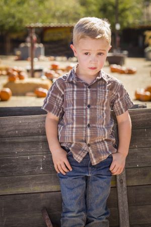 Little Boy Standing Against Old Wood Wagon at Pumpkin Patch in Rural Setting