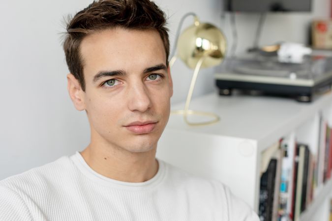 Confident young man relaxing at home on the sofa looking up at camera