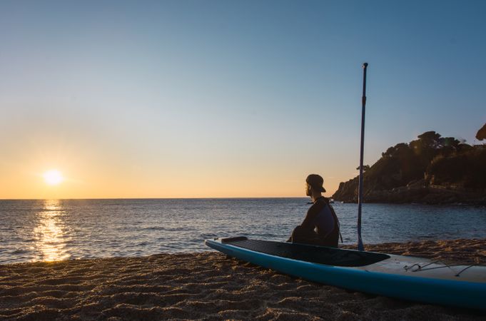 Man practicing paddle surfing with neoprene in a sunrise