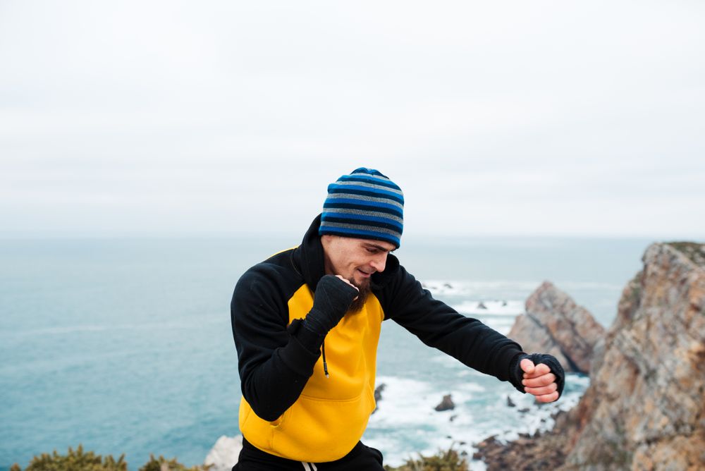 Kickboxer training on cliff near sea