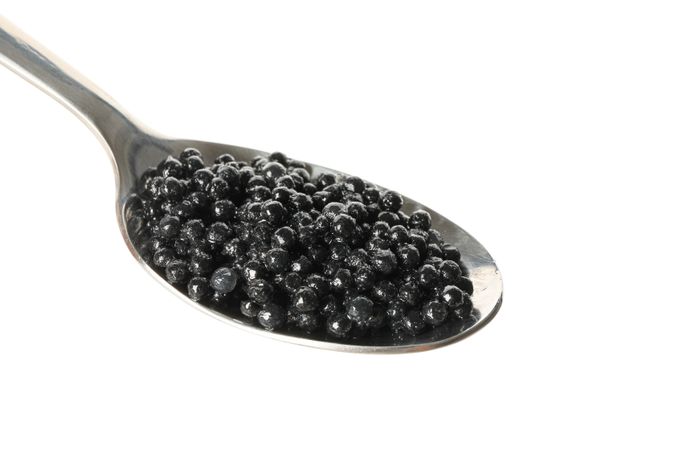 Spoon with caviar isolated on plain background
