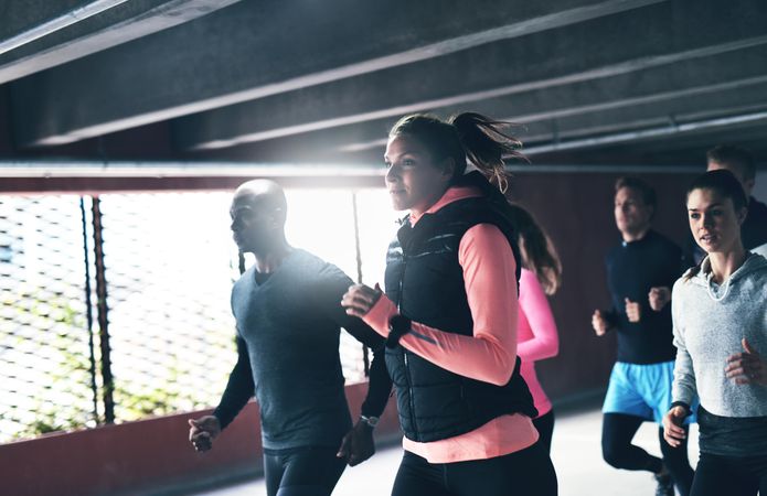 Woman leads a group of runners in an industrial concrete space