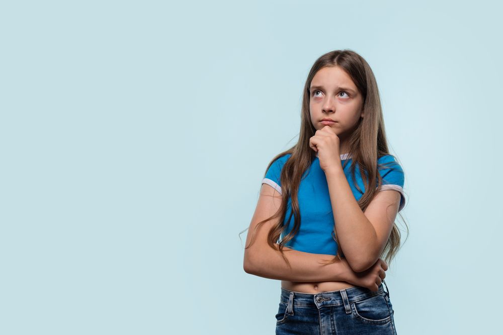 Pensive girl holding chin while deep in thought.