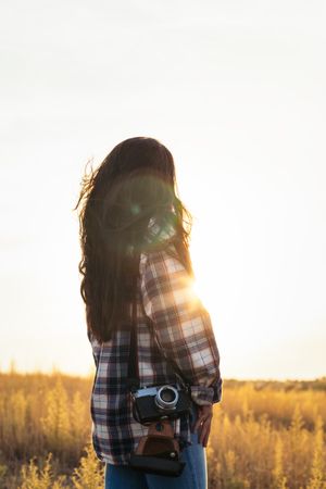 Young woman dressed in vintage clothing watching the sunset in the field