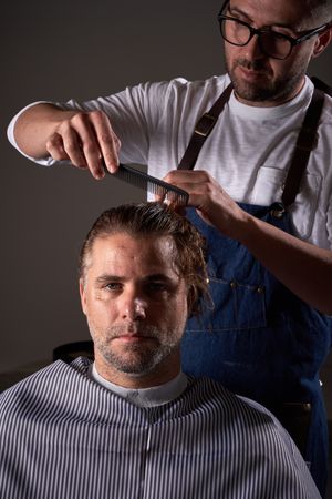 Barber cutting hair of man