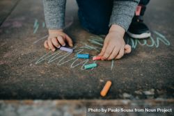 Child playing with colorful chalk 4AMQR4
