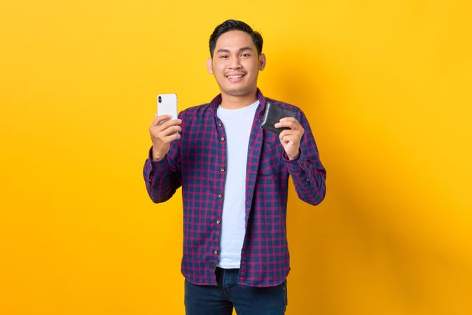 Happy man holding smart phone and wallet