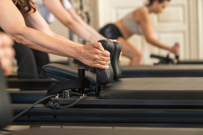 Women exercising in a row on reformer machines during a group pilates class at a modern fitness studio.