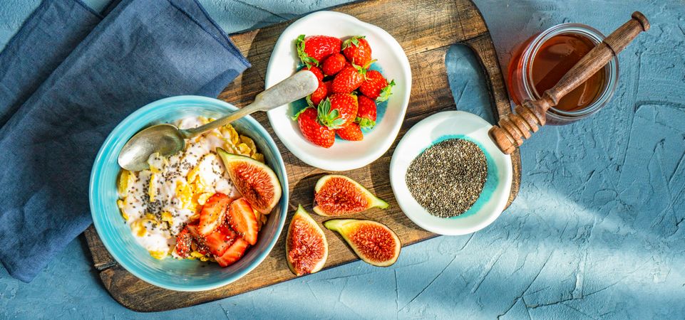 Top view of traditionally healthy breakfast with chia, honey, figs and strawberry on board