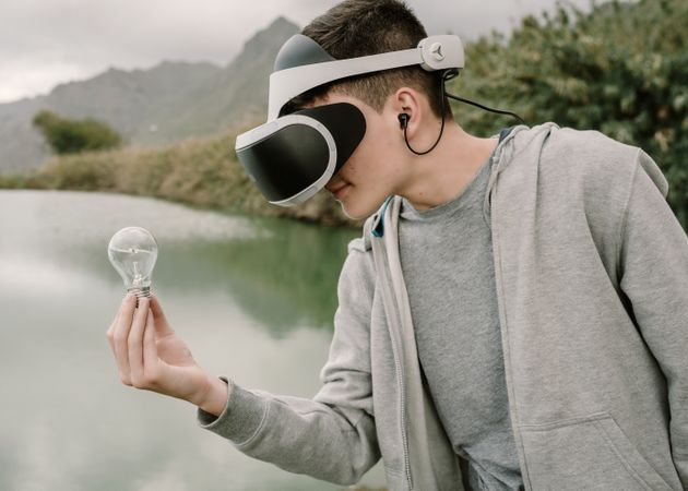 Young teenager with virtual reality glasses holding a light bulb