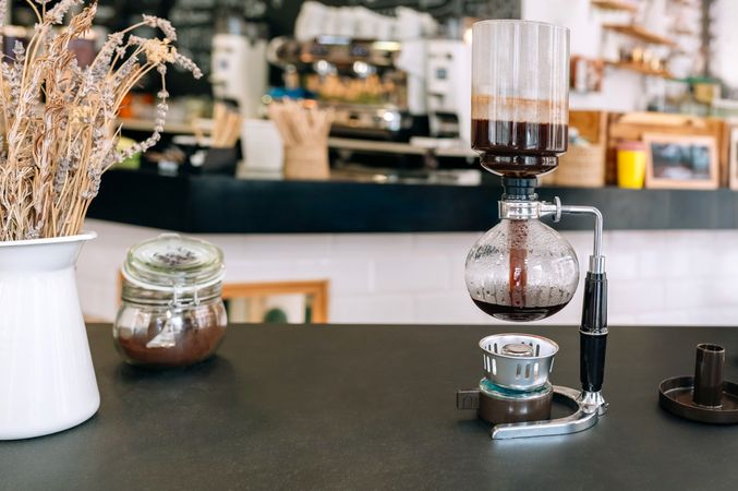 Brewing coffee with Japanese siphon maker in a empty modern cafe setting