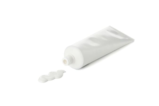 Blank tube with toothpaste isolated on light background