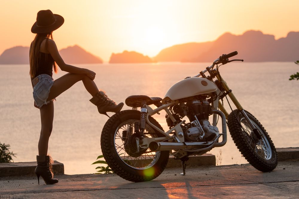 Woman tying boots near motorcycle